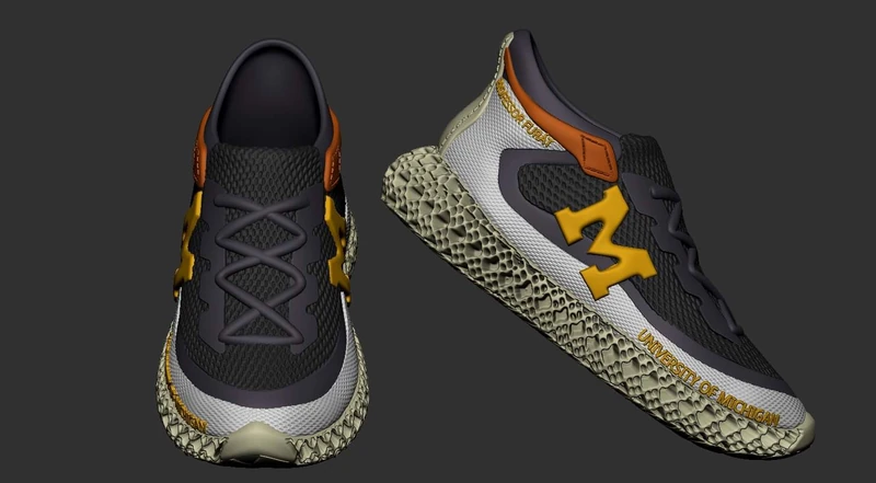 3D model of a running shoe seen from the front and the side, with a block M on the side and University of Michigan lettering along the sole.