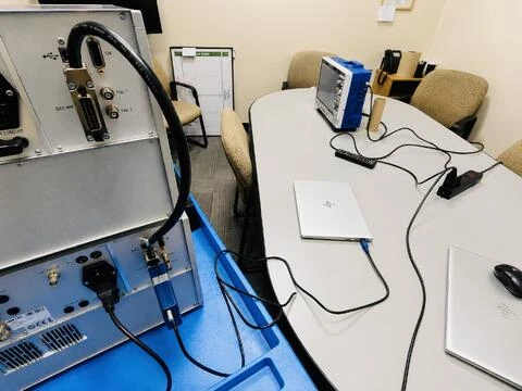 Test equipment on a blue cart, with cables running to an oscilloscope and a laptop on a table.